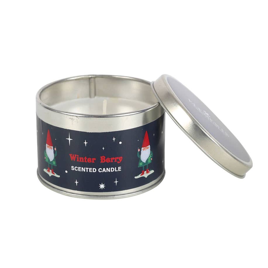 The "Gnome Sweet Gnome" candle is presented in a round tin with a slightly open lid, revealing its charming design against a blue background. Its Winter Berry scent is ideal for infusing your winter home decor with warmth and character.