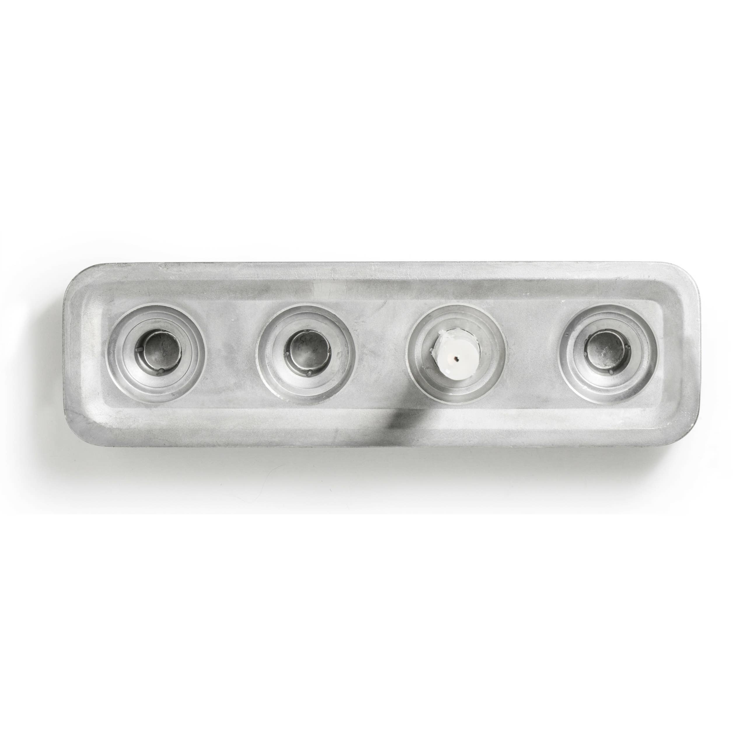 The rectangular ice cube tray with four circular molds, viewed from above and reminiscent of the Stumpastaken Polished Aluminum Swedish Candle Holder, is partially empty. Made from recycled aluminum, it blends practicality with innovative spirit.