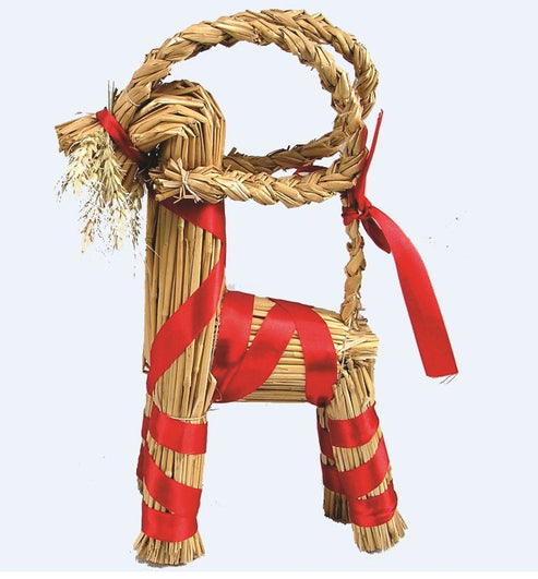 The Straw Goat Julbok Figurine, approximately 12" tall, is crafted from straw and adorned with red ribbons—a charming piece of Scandinavian decor.