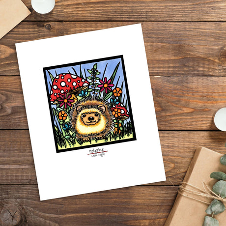 The "Hedgehog Art Print" by Sarah Angst is a framed giclée reproduction (11"x14" or 8"x10"), featuring a hedgehog with mushrooms and flowers—an enchanting woodland decor piece for your space.