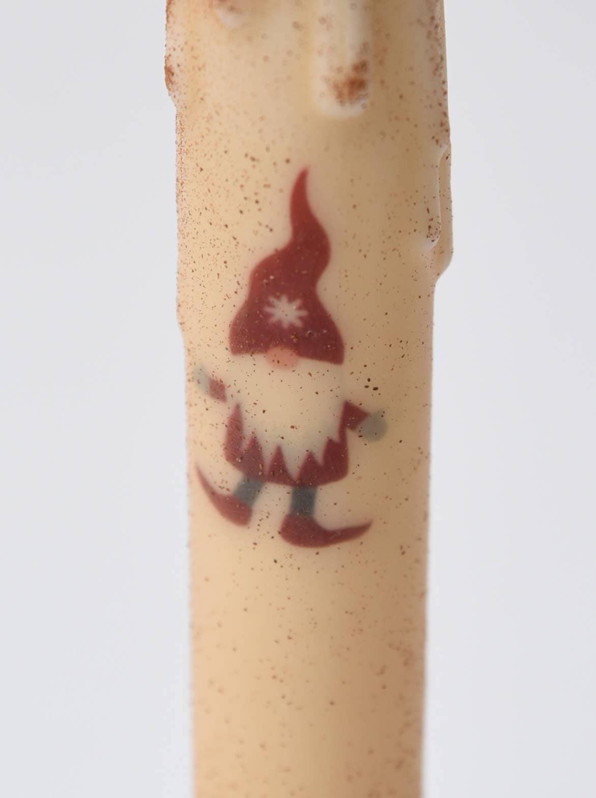 Close-up of the Candle: Christmas Gnome LED Timer Taper Candle: Cinnamon Dusted, showcasing a beige body with a gnome in a red hat and boots, white beard, and warm festive LED glow.