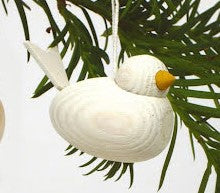 The Ornament: Wooden Scandi Bird White Christmas Tree Ornament features a handmade wooden bird with a yellow beak hanging from a green pine branch, adding Scandinavian charm to your Christmas decor.