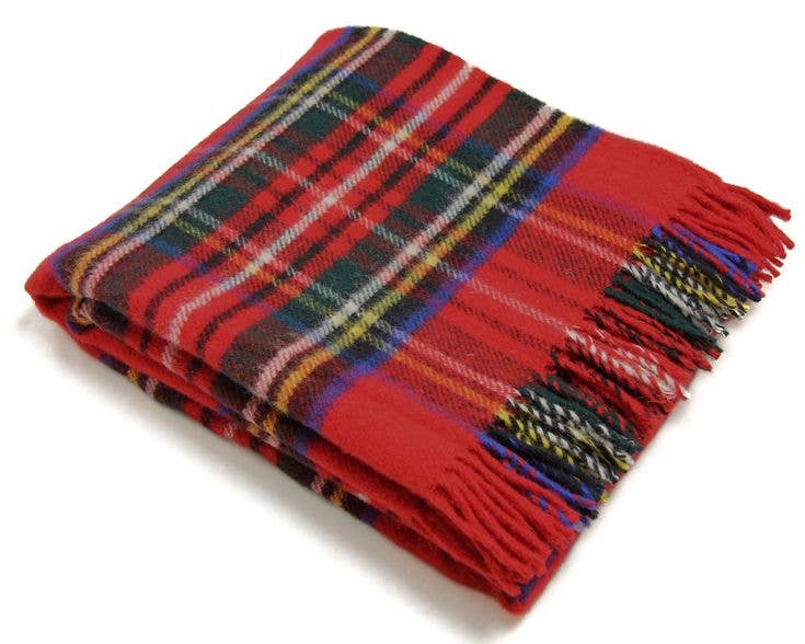 The Royal Stewart Deluxe Highland Blanket is a folded red tartan blanket with fringed edges, showcasing classic Scottish patterns in black, green, yellow, and white.