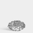 Clear glass votive holder with an irregular, sculpted textured surface, displayed against a plain light gray background.