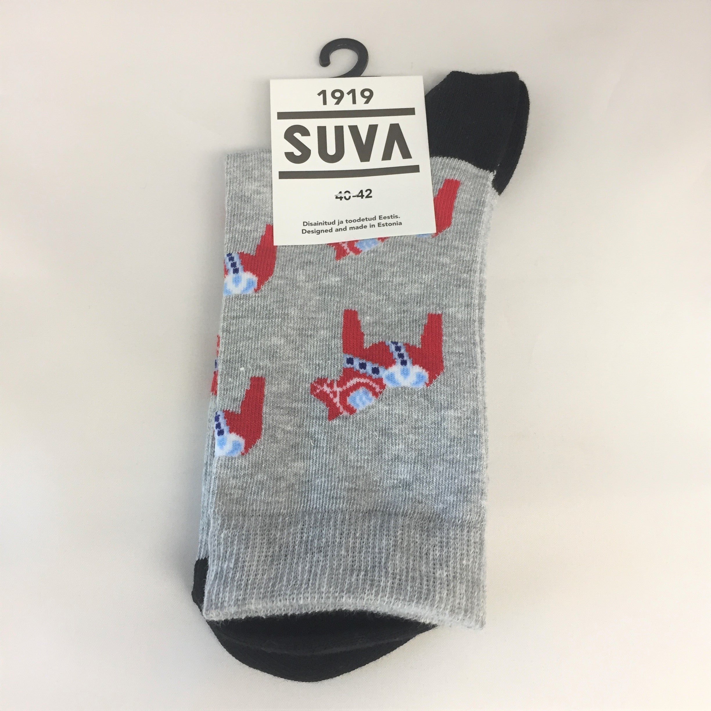 Gray socks decorated with red Swedish Dala horses, black toes and heels, hang neatly packaged from a black hook. The label reads 1919 SUVA, part of the Nordic Collection, available in size 36-38.