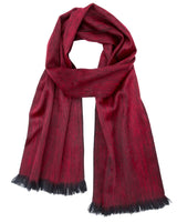 The Alpaca Scarf in sapphire red features black fringe and is displayed laid flat on a white background.