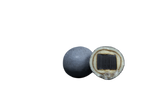 Two round Nordic licorice candies on a white background; one is whole, the other is halved to show a black center, white middle layer, and gray outer coating.