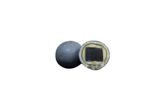Two round Nordic licorice candies on a white background; one is whole, the other is halved to show a black center, white middle layer, and gray outer coating.