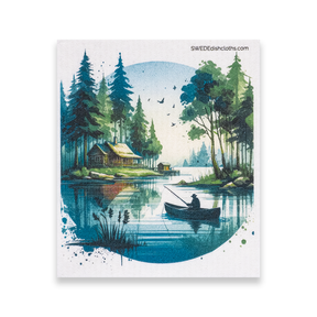 A Swedish Dishcloth featuring an illustration of a person fishing from a boat on a calm lake, with surrounding trees and a cabin in the background.