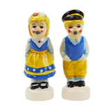 Two ceramic figurines resemble a magnetic kissing couple dressed in colorful traditional attire: the girl in a yellow dress and the boy in a blue vest with a cap. These Shakers: Swedish Couple Salt & Pepper Shakers make an enchanting Scandinavian gift.