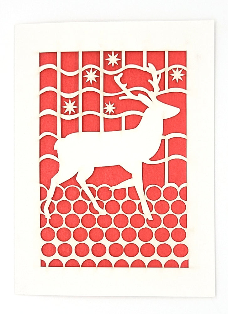 A white reindeer cutout set against a red backdrop featuring snowflakes, stirring up a festive mood.