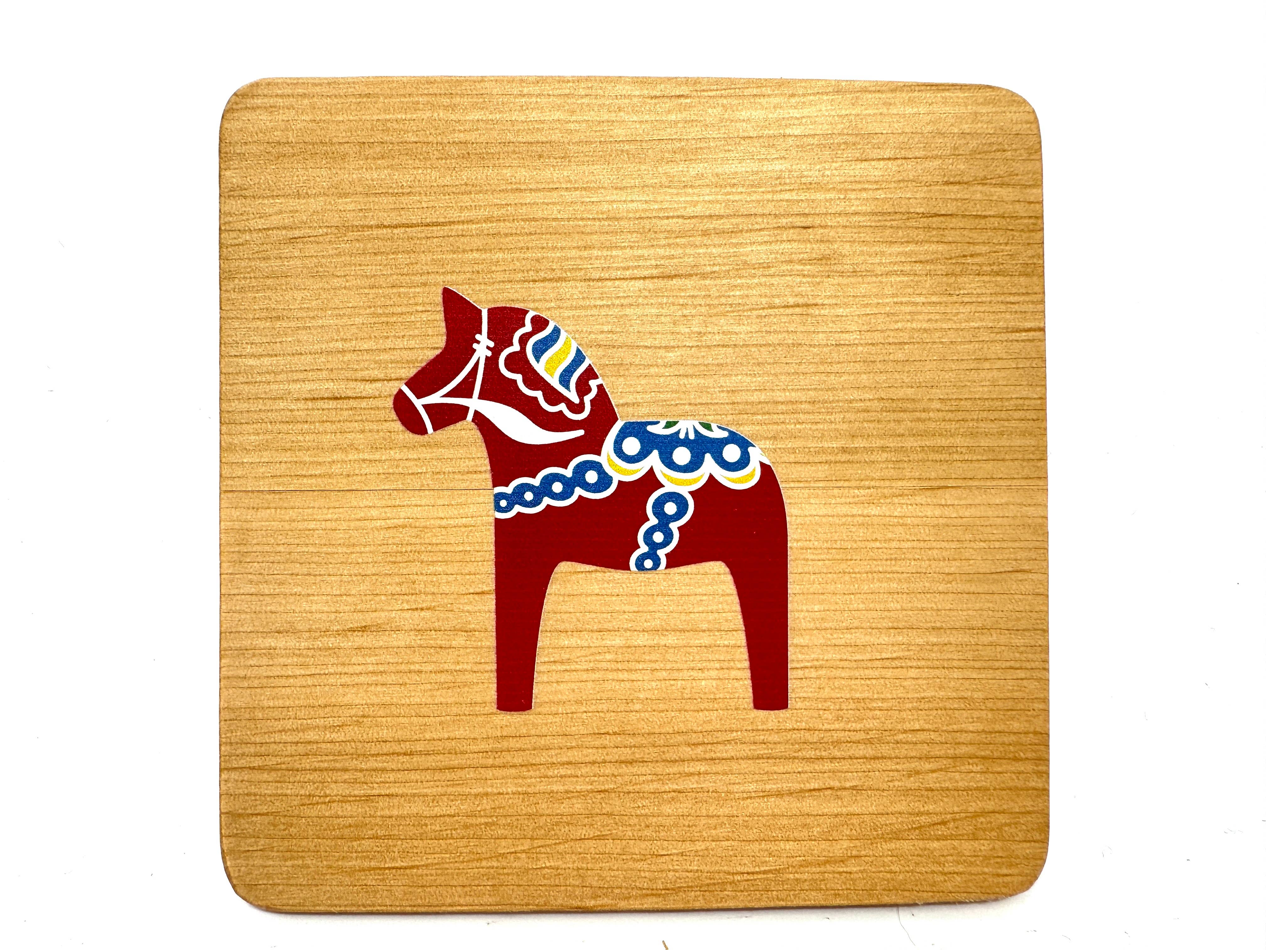 The 4" square alder wood coaster features a red Dala Horse with colorful kurbits, combining Swedish tradition and vibrant design.