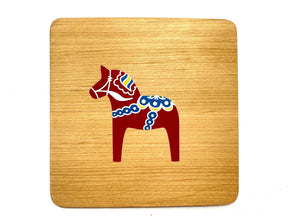 Part of the Bundle: Dala Horse Kitchen Accessories, this alder wood coaster features a red Dala horse with blue, white, and yellow accents on light wood—a charming touch for Scandinavian decor or kitchen collections.