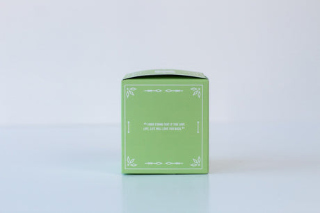 A small green box with white decorative lines and a quote on the front, ideal for gifting the Soap: Coconut Island Bath Bomb or other skin-nourishing bath bomb treats, photographed on a plain light background.