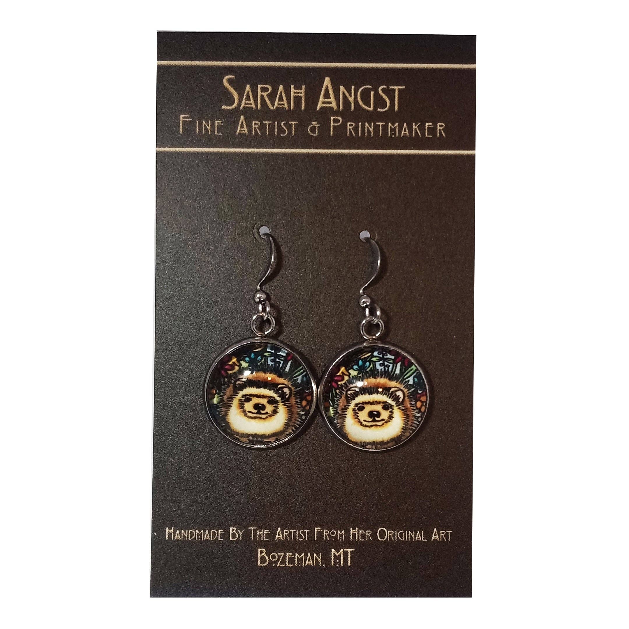 Pair of hedgehog-themed handmade earrings on a card labeled Sarah Angst Art, Fine Artist & Printmaker, Bozeman, MT.