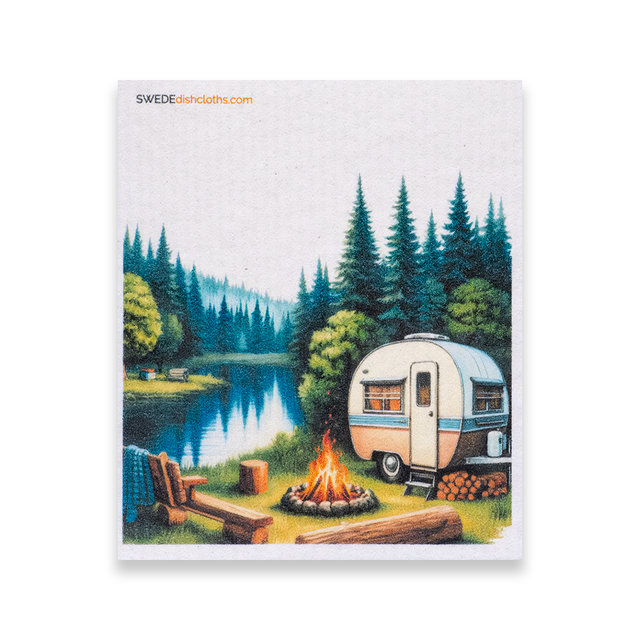 Swedish dishcloth with an illustration of a camper trailer by a lake, surrounded by pine trees and a campfire, in a Nordic wilderness style.