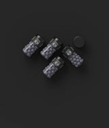 Four black jars containing dark round Nordic candies, similar to salty licorice, arranged on a black background. One jar has its lid placed next to it.