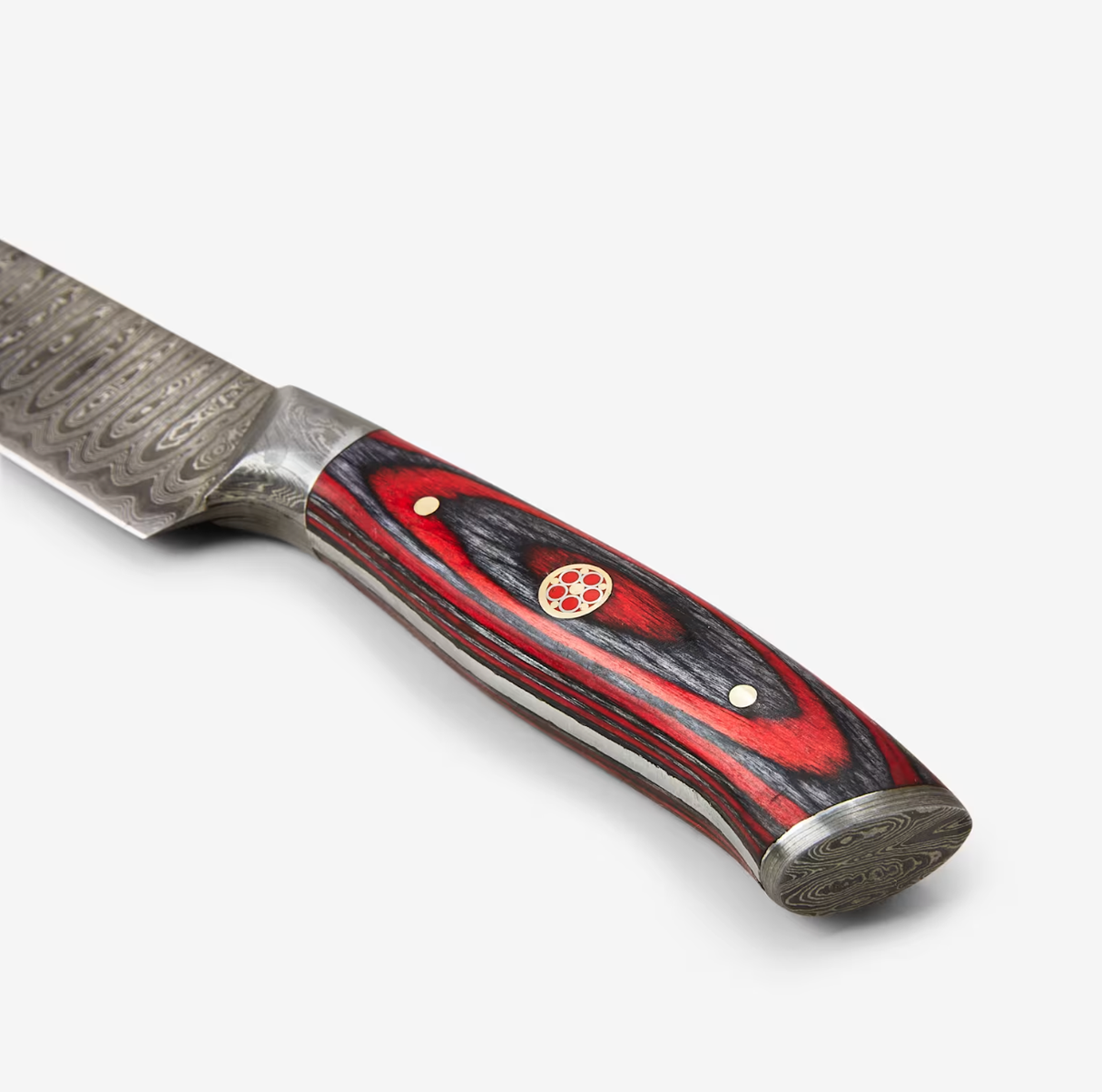 Close-up of a Damascus steel knife handle with red and black wood grain, gold rivets, and a patterned blade.
