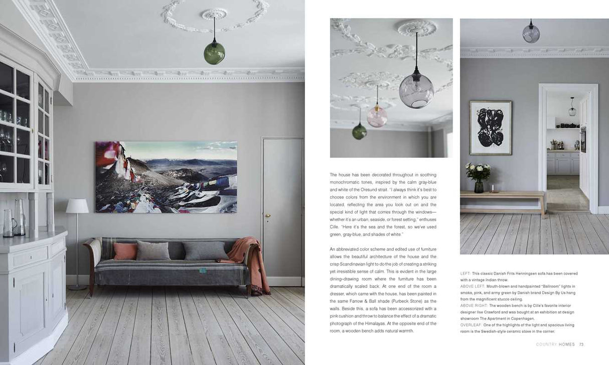 A bright, elegant living room with natural light, white molding, pale wood floors, a gray sofa, wall art, and glass pendants. Next door, flowers on a console table echo the Scandinavian style in Scandinavian Home Interiors Inspired by Light by Niki Brantmark.