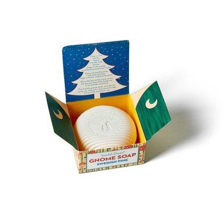 A round white Gnome Soap Swedish Pine Swedish Dream Bar Soap rests inside an open, colorful box featuring a tree illustration and printed text beneath the lid.