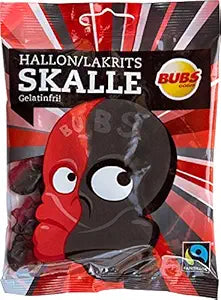 The Candy: Bubs - Raspberry Licorice Skulls (90g) offers a distinctive fusion of raspberry and licorice flavors, presented in a skull design. This Swedish treat is Fairtrade certified and features a two-toned face graphic.