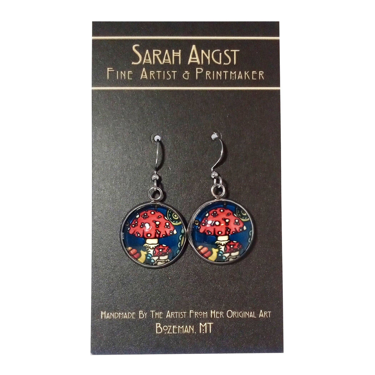 Earrings adorned with vibrant mushroom illustrations on a mini giclee print card, created by the renowned fine artist and printmaker from Bozeman, MT, Sarah Angst.