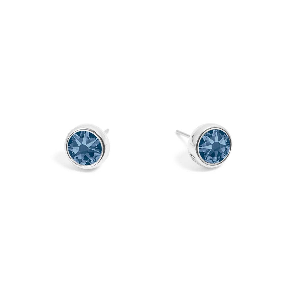 A pair of silver stud earrings, featuring denim blue Swarovski crystals from A&C Oslo, displayed on a white background.