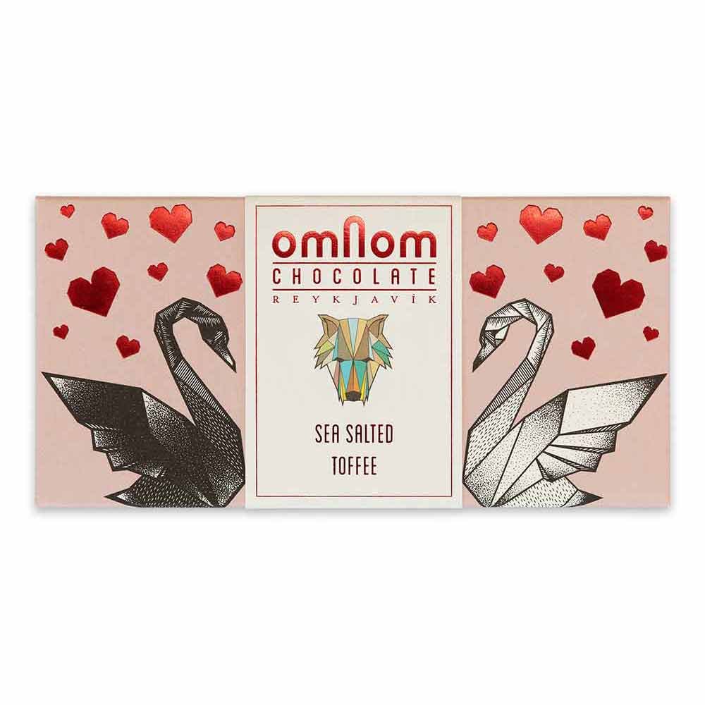 Rectangular OmNom Toffee + Sea Salt 60g wrapper, decorated with black and white origami swans, red hearts, and text reading White Caramelised Chocolate & Sea Salt and Reykjavik.