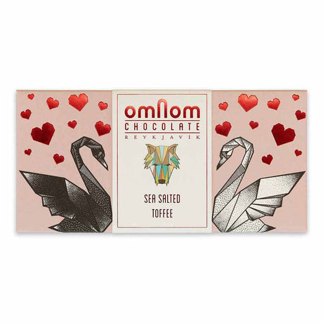 Rectangular OmNom Toffee + Sea Salt 60g wrapper, decorated with black and white origami swans, red hearts, and text reading White Caramelised Chocolate & Sea Salt and Reykjavik.
