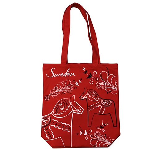 A perfect Nordic souvenir, the red Swedish tote bag features white Dala horse designs and Sweden at the top, known as the Red Swedish Bag with Dala Horses & Kurbits.