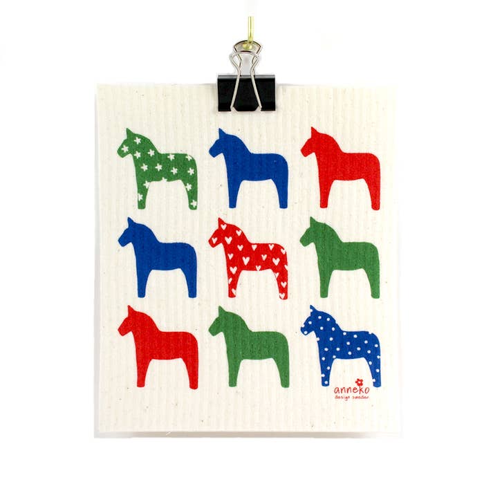 The Dalahäst Dala Horses Dish Cloth features nine uniquely patterned, stylized horse figures in red, blue, and green. This eco-friendly dishcloth is biodegradable and compostable, offering not just visual delight but also a sustainable cleaning choice.