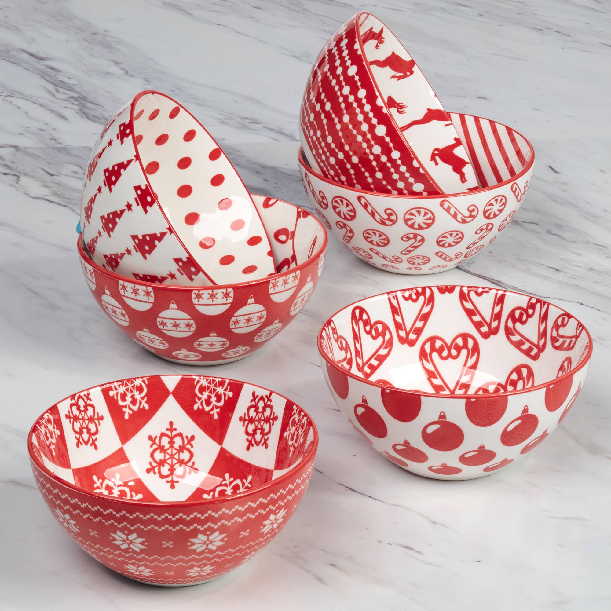 Five Peppermint Candy Christmas All Purpose Bowls (4.75x2.25), each with red and white holiday designs—trees, ornaments, hearts, reindeer, and snowflakes—are arranged on marble. Ideal as a festive porcelain bowl set for gatherings.