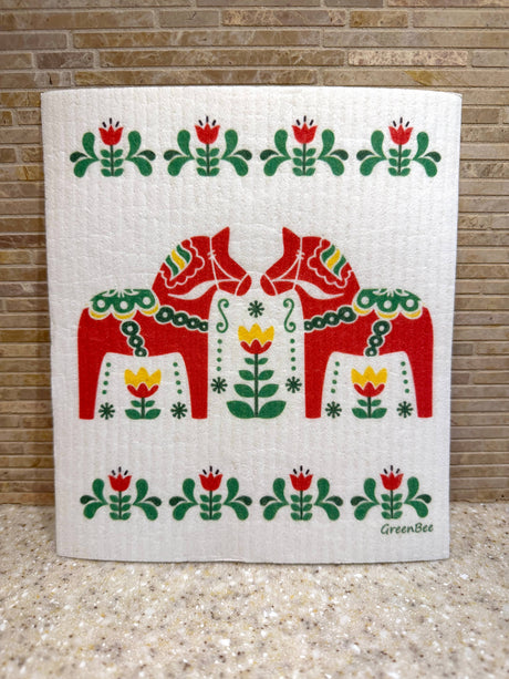Swedish dishcloth with two red Dala horses surrounded by green and yellow floral rosemaling patterns.