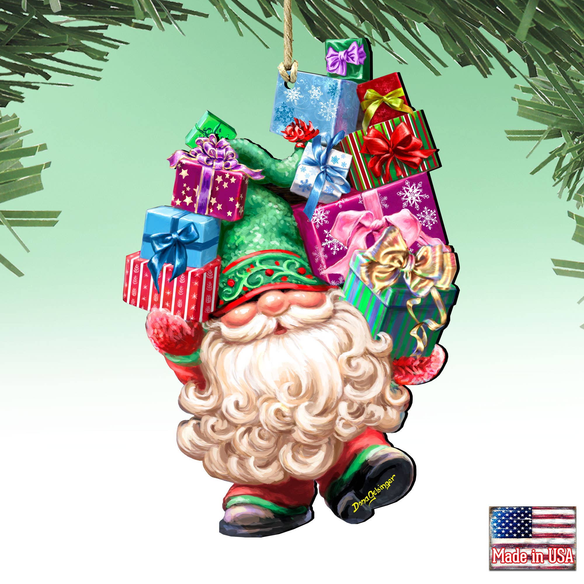 The Christmas ornament, named "Gift Giver Gnome Handcrafted Ornament D.Gelsinger," showcases a cheerful gnome carrying stacked colorful gift boxes, adorned with festive patterns and crafted in a unique style. A "Made in the USA" label is featured in the corner.