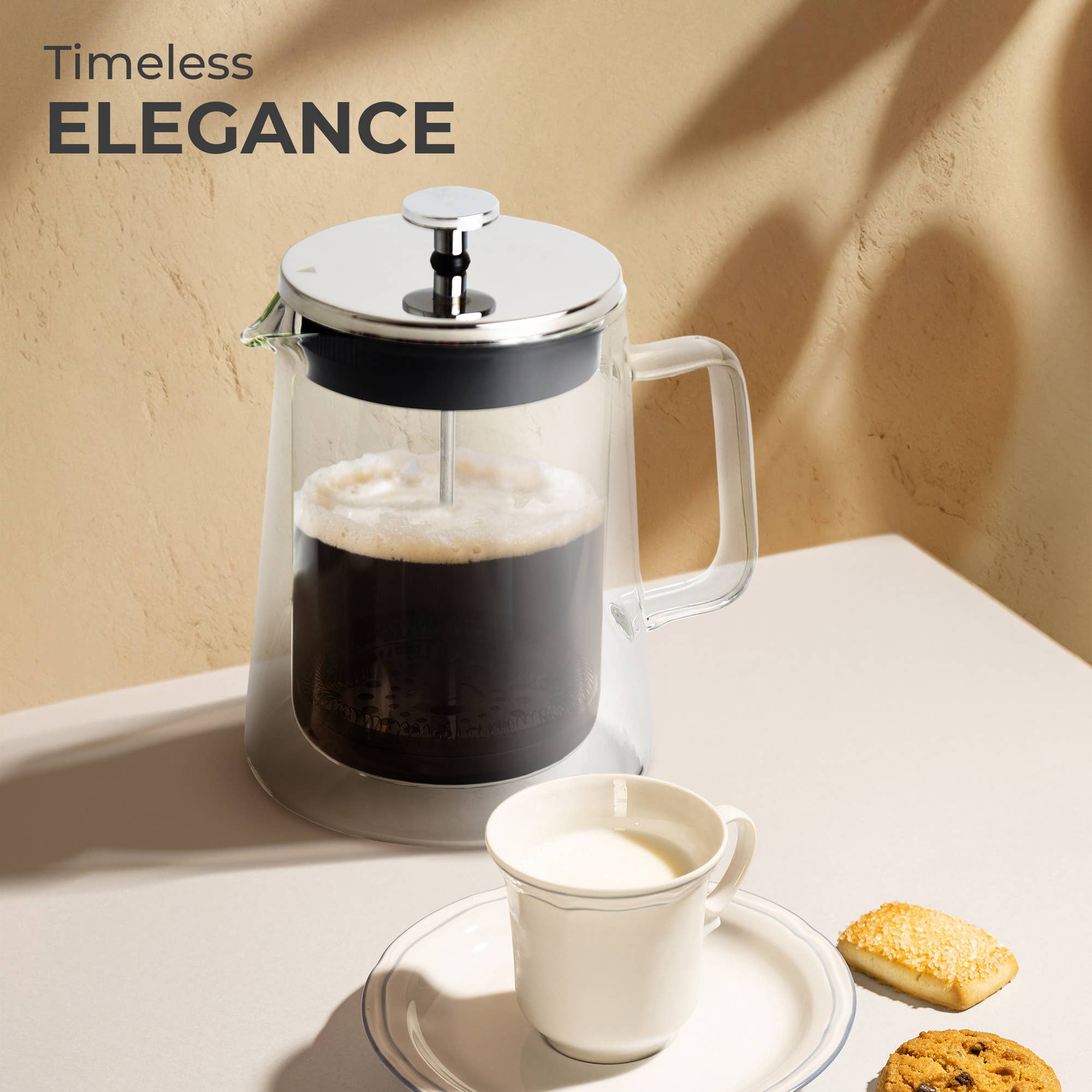 A Kaffe French Press Coffee Maker – Double-Wall Borosilicate Glass (0.8L) sits on a beige table with a white cup, saucer, and cookies under soft lighting. “Timeless ELEGANCE” appears in the corner.