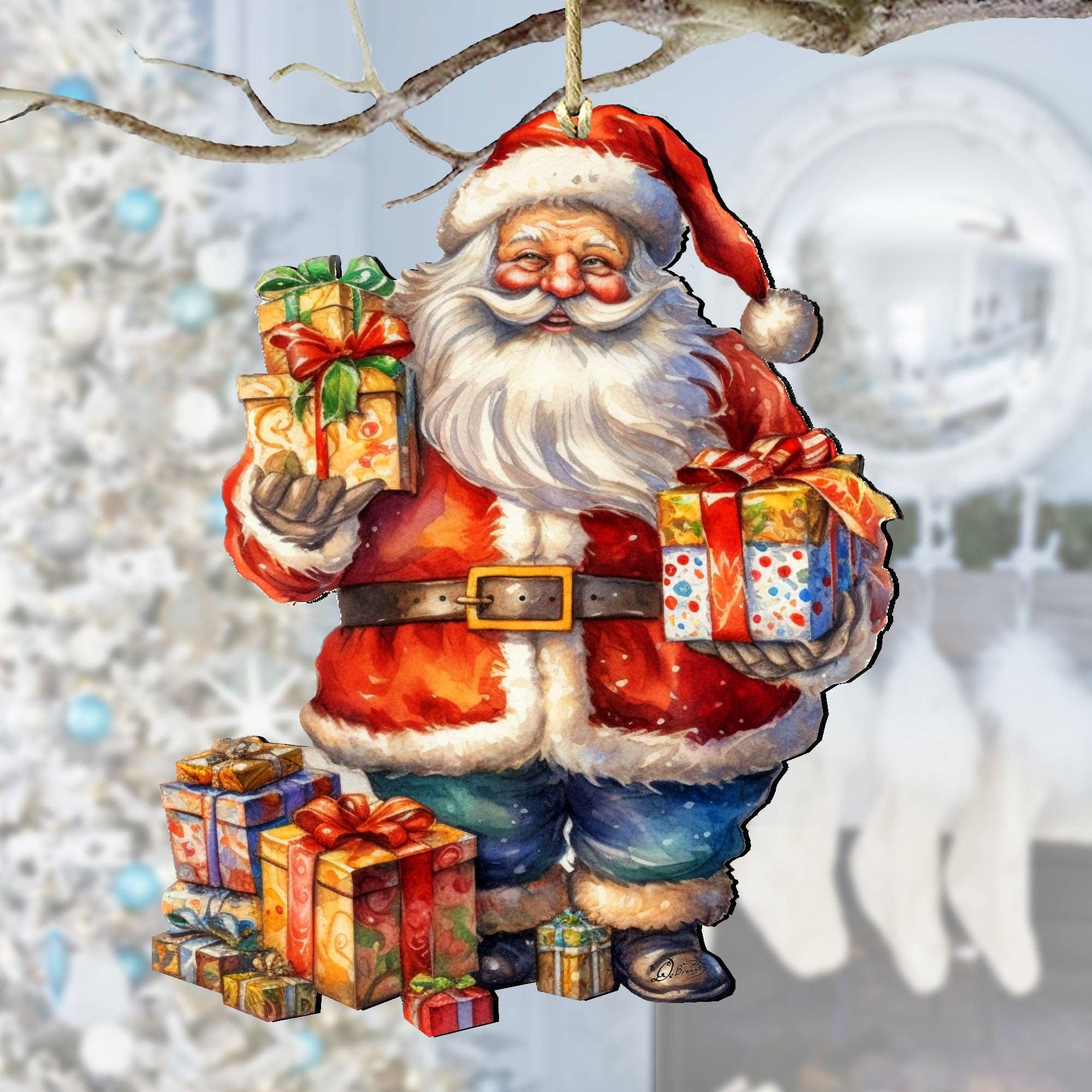 The Ornament: Merry Delivery Santa Wood Christmas Tree Ornament by artist G Debrekht features Santa holding wrapped gifts, with extra presents at his feet, set against a blurred white Christmas tree and stockings in the background.