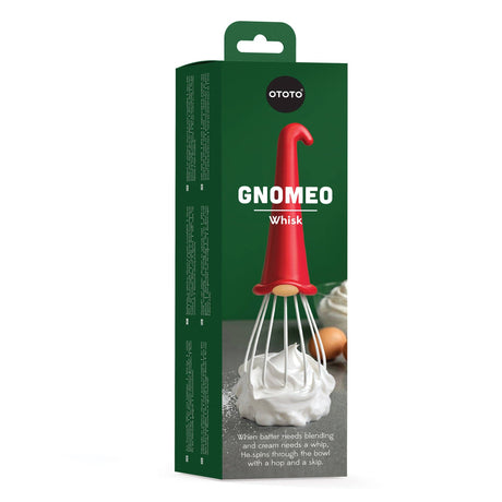 Whisk: Gnome Wire Whisk by OTOTO comes in playful green box packaging, showcasing a whimsical red gnome whisk with a hat-shaped handle and white wires, pictured alongside eggs and whipped cream on the front. The text highlights this kitchen helper's charming design—blending batter or whipping cream with a hop and a skip—making it an ideal, giftable baking tool for any home baker.
