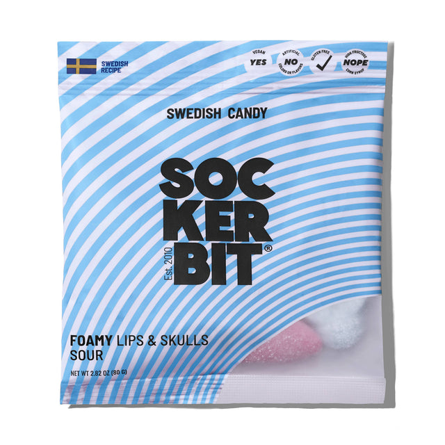 A 2.8oz Sockerbit bag of Foamy Lips & Skulls Swedish Candy with blue and white stripes, a Swedish flag, and pink and white foamy candies visible inside. Made with a traditional recipe.