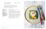 Inspired by the book "Scandinavian Year" by Bronte Aurell, this open-faced sandwich with asparagus, poached egg, herbs, and seeds offers a fresh taste of Nordic cuisine—served on a speckled plate with fork and knife to the right.