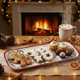 Melamine tray with cookies and cupcakes on a wooden table in front of a fireplace, with hot cocoa, pinecones, and holiday decorations in the background.