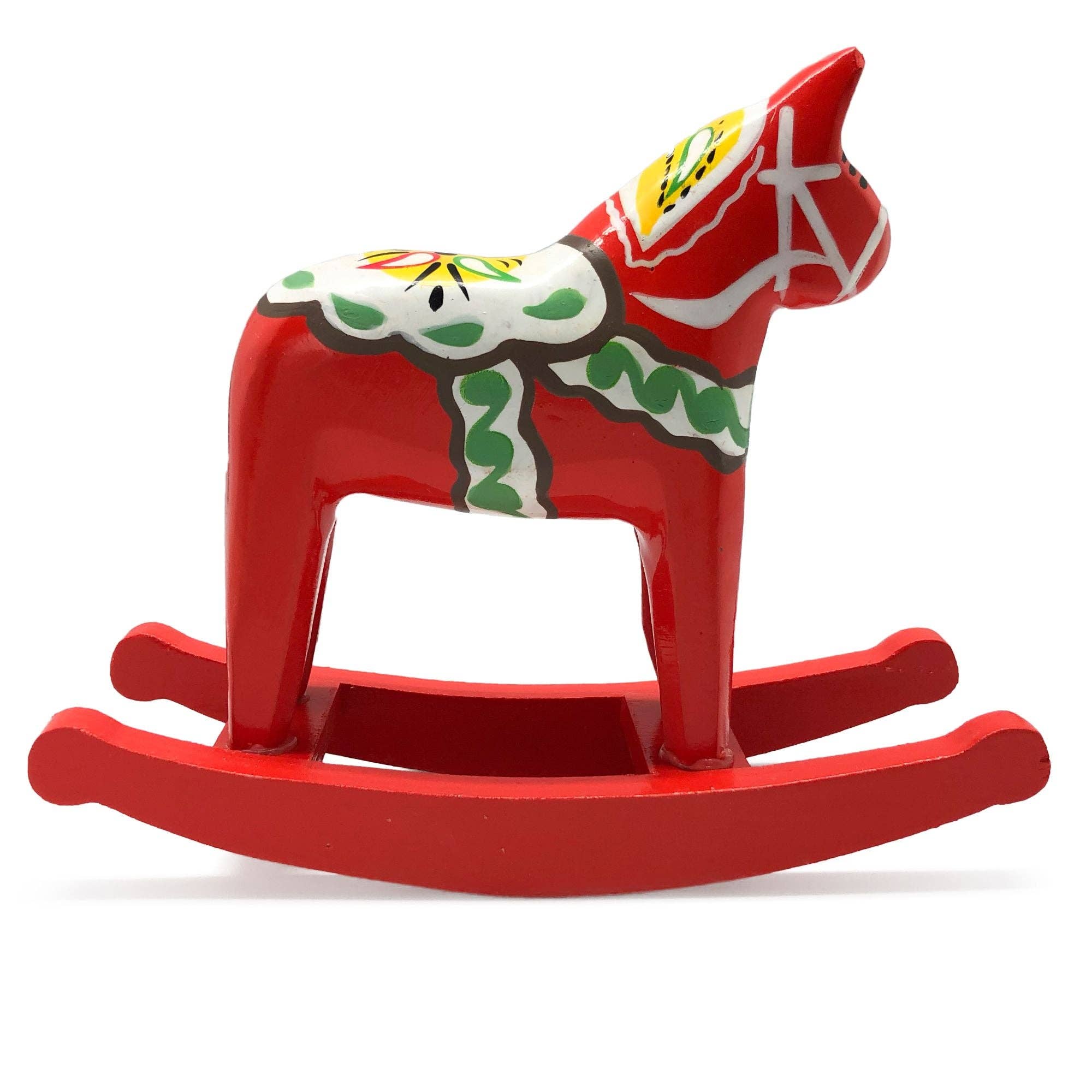 A medium-sized rocking horse, adorned with charming Scandinavian motifs and featuring a red-painted wooden design complemented by decorative green and white patterns, reflecting the theme of a Swedish Dala horse.