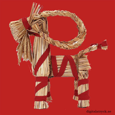 Straw Swedish Yule goat with red ribbons wrapped around its body and legs, positioned on a solid red background.