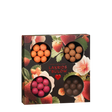 Showcasing the Candy: Gift Box LOVE 2026—a square selection box from Lakrids by Bülow Denmark—this arrangement features four round windows displaying assorted colored chocolate-coated licorice balls. The gluten-free LOVE box stands out against a vibrant floral and strawberry-patterned background, offering an enticing selection of confections.