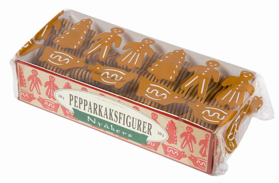 A festive box of Nyakers Peppar Kakor Holiday Shapes Gingerbread cookies, featuring gingerbread crafted into shapes of people, animals, and Christmas trees, adorned with delicate white icing details and nestled in clear plastic packaging.