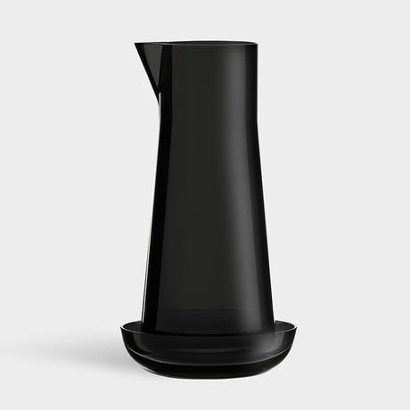 The Orrefors: Carafe with Bowl features a tall, black carafe designed by Björn Dahlström, paired with a matching shallow bowl and photographed against a plain light background.