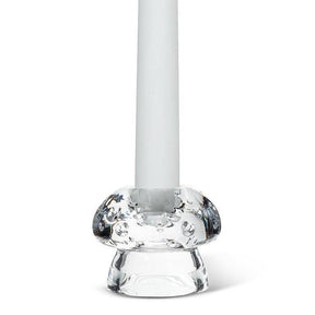 A white candle stands upright in the Mushroom Glass Taper Candle Holder, which measures 2" tall by 2.5" in diameter and features a rounded, textured base inspired by mushroom decor.