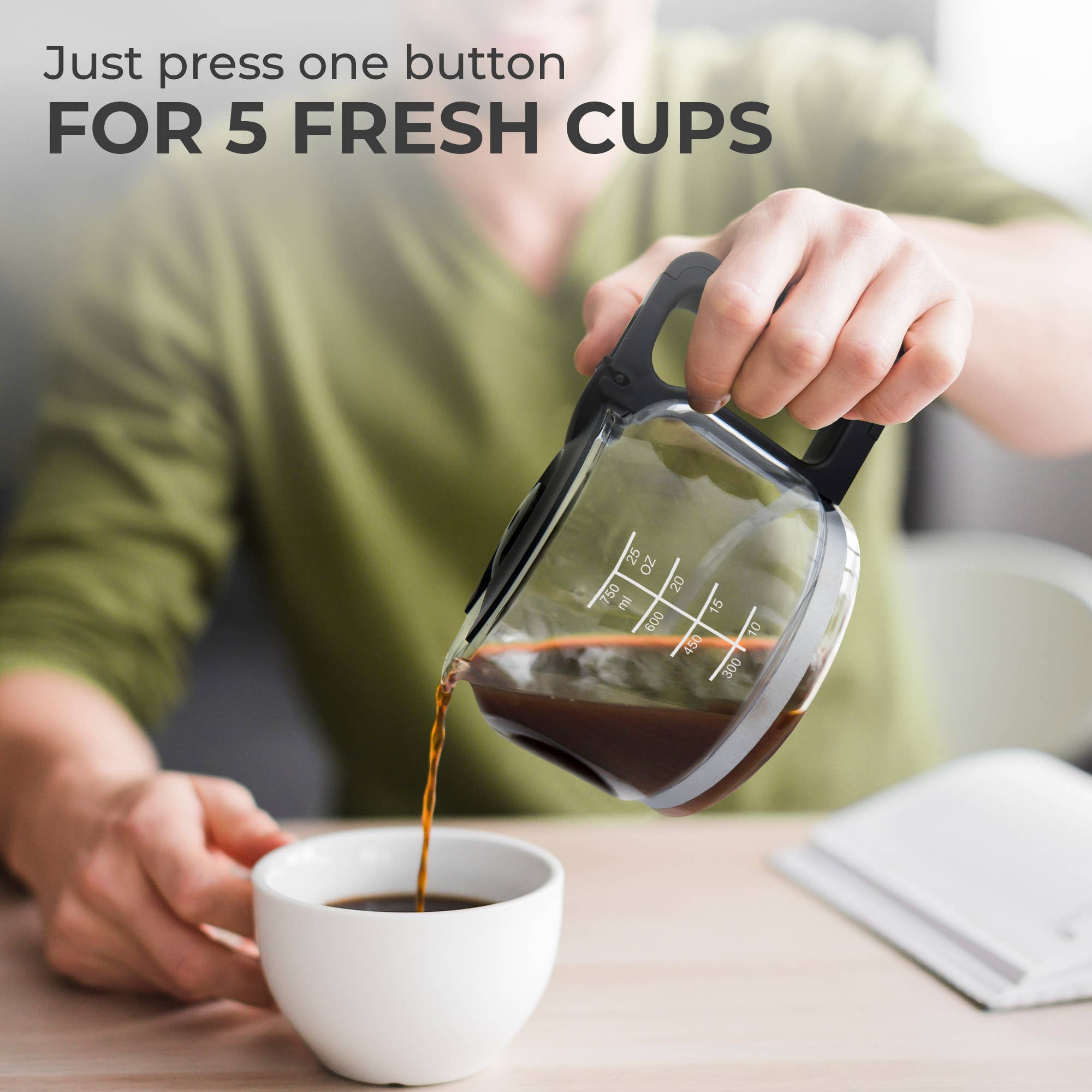 A person pours coffee from the glass carafe into a cup, with text: “Just press one button for 5 fresh cups.” An open notebook sits nearby—perfect while the compact Kaffe 5-Cup Coffee Maker w/ Scoop brews using its reusable filter basket.