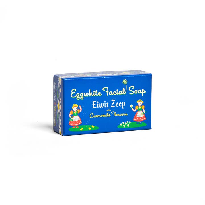 A blue box labeled Soap: Eggwhite & Chamomile Facial Soap – 2.25 oz features illustrated women in traditional dress. This gentle cleanser blends eggwhite and chamomile for a soothing daily facial care experience.