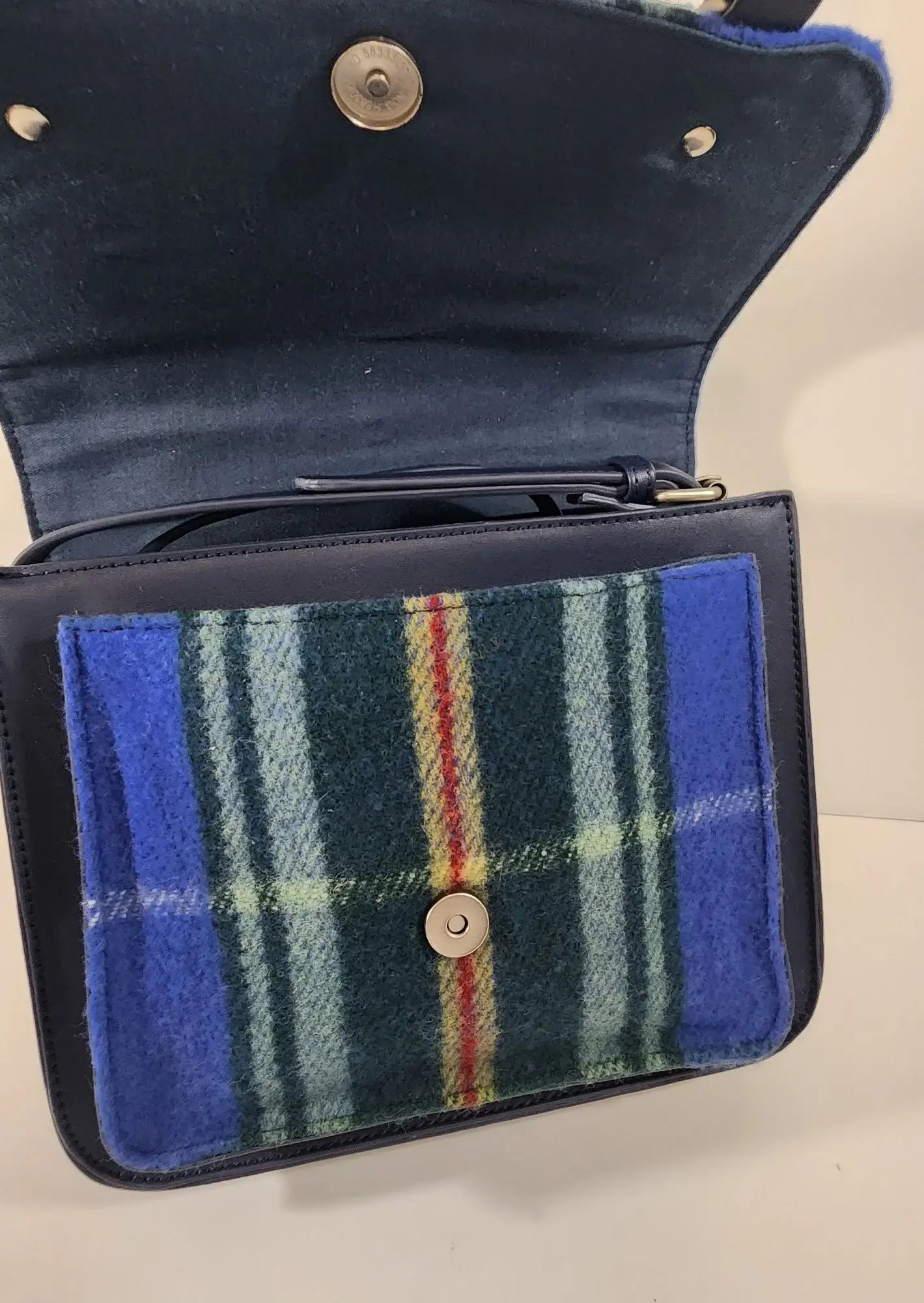 The Bag: Nova Scotia Patsy Handbag features an open flap, button closure, and a front pocket with blue, green, and yellow plaid—a charming provincial tartan bag inspired by classic Nova Scotia designs.
