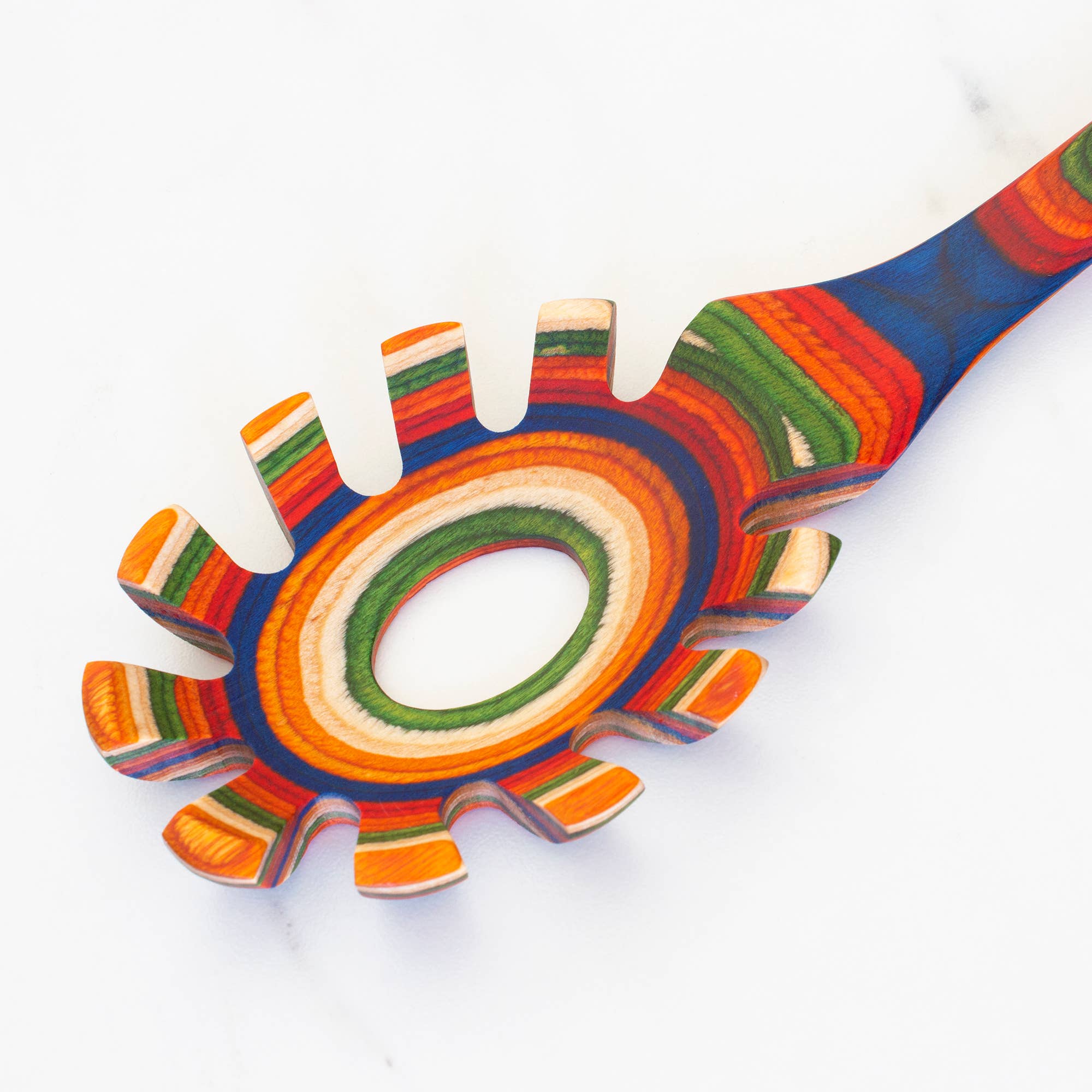 Introducing the Marrakesh Collection Spaghetti Server, a colorful spaghetti spoon featuring a vibrant striped pattern of red, orange, blue, and green on a white background. Made from birch wood, this non-stick utensil adds flair to any kitchen while making pasta handling effortless.